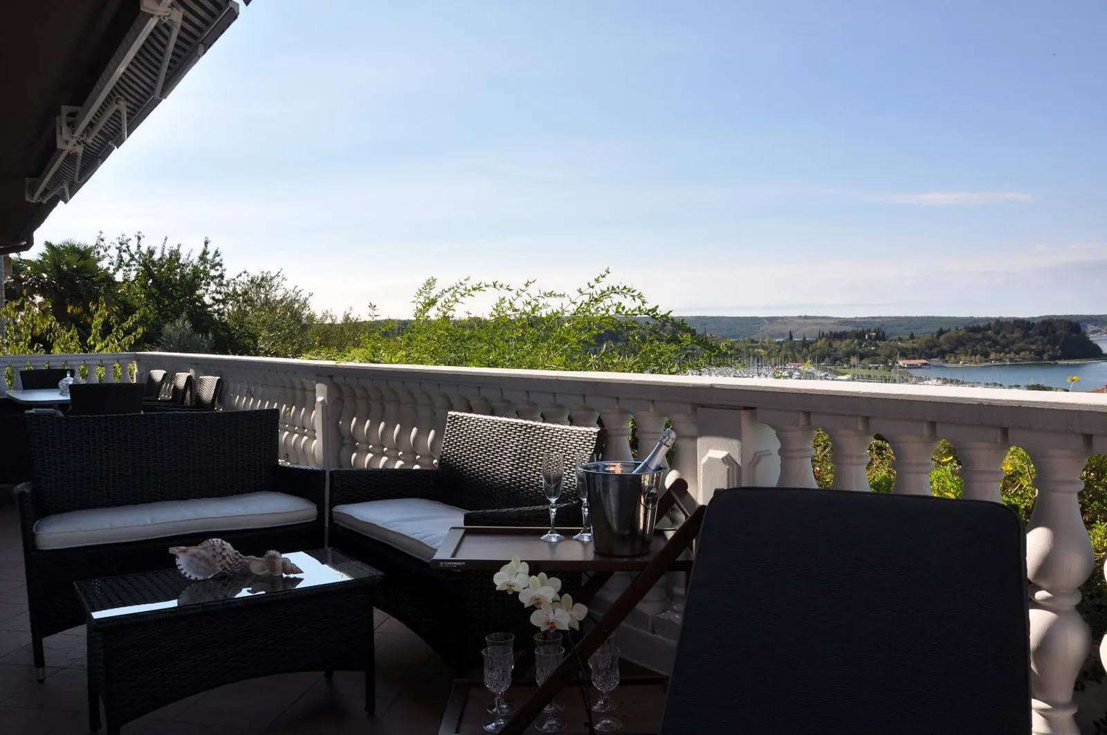 Balkon z belo balustrado, pleteno garnituro in pogledom na morje